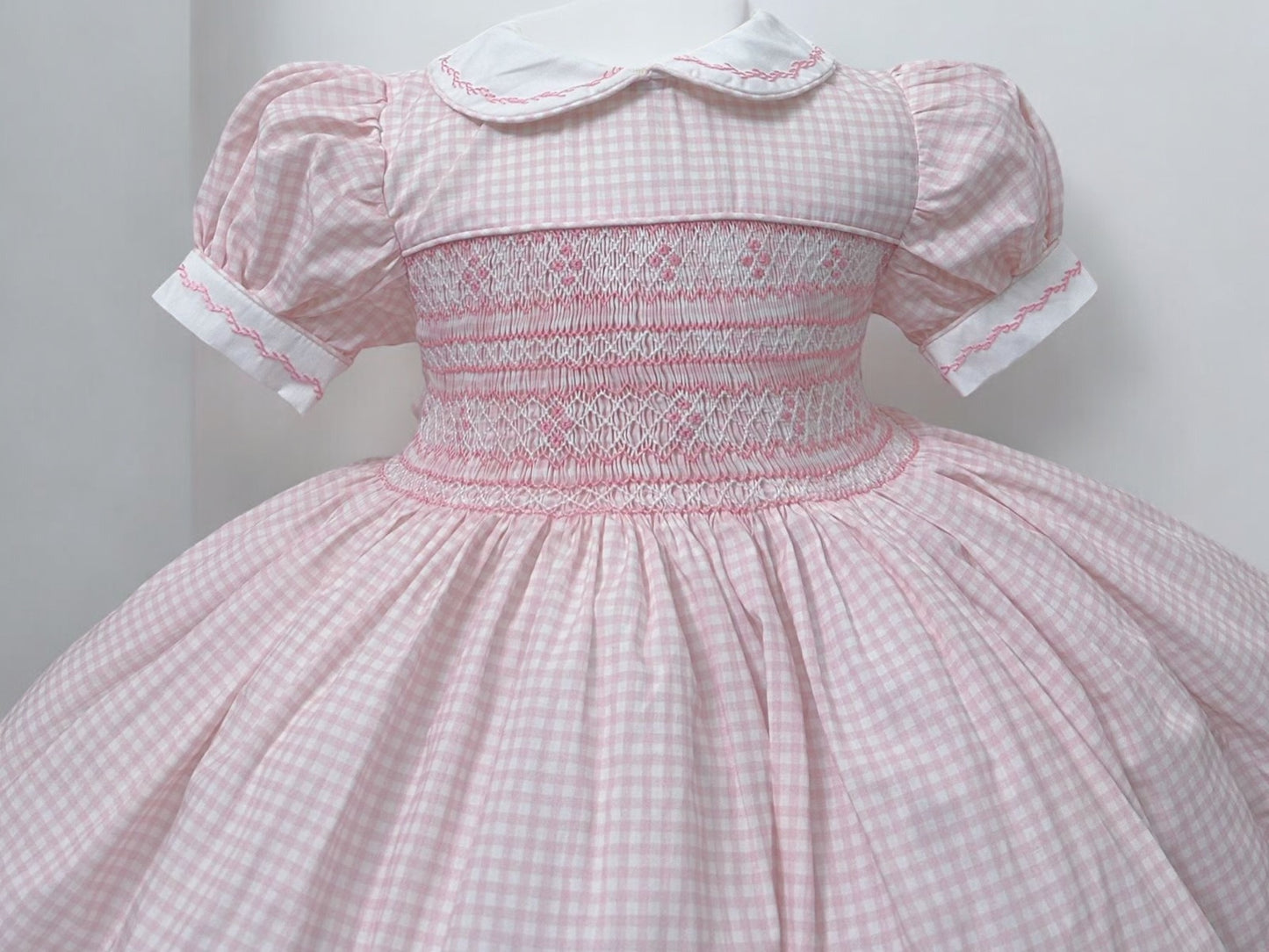 Pink gingham smocked dress. Fitted petticoat and comes with knickers and hair bows