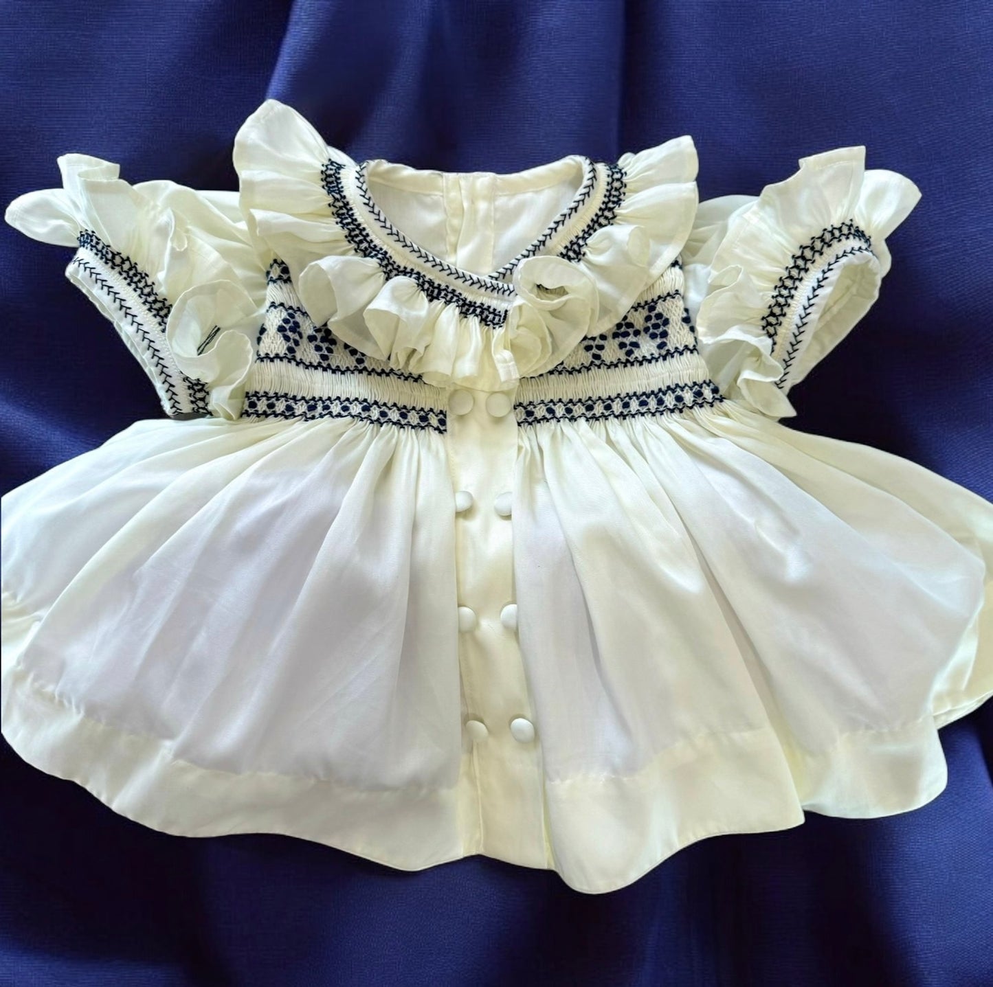 Cream dress with navy smocking on chest sleeve and collar