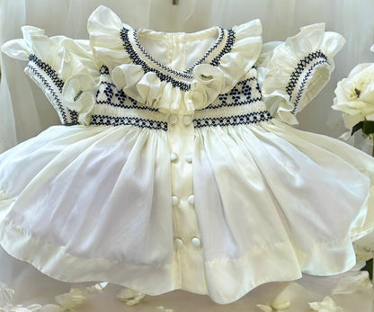 Cream dress with navy smocking on chest sleeve and collar